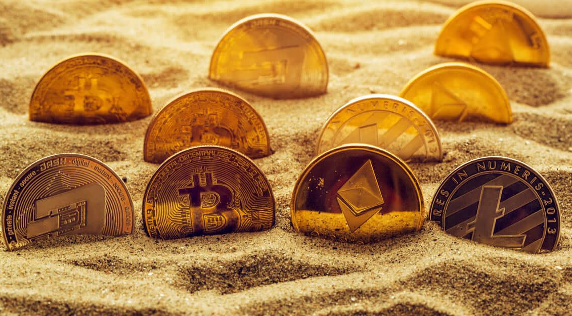 cryptocurrency coins in sand